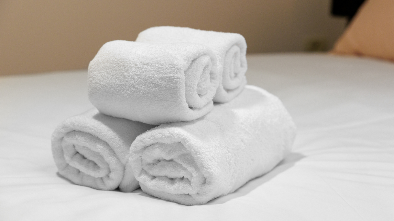 Stack of white towels on a bed after neat services group team make the flat ready for new host as airbnb cleaning booked in london